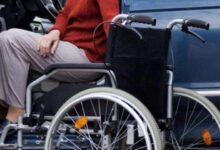 Tekerlekli sandalye kullanıcı engelli birey, otomobilin sürücü koltuğundan tekerlekli sandalyeye geçmeye çalışıyor.