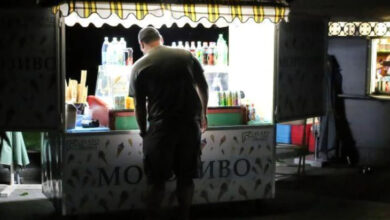 Karanlık bir sokakta seyyar bir tezgah üzerinde su ve dondurma satışı yapılıyor.