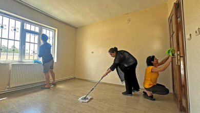 Oturma odasında 3 kişi temizlik yapıyor.