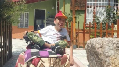 Akülü tekerlekli sandalye üzerinde oturan spastik engelli birey olan Murat Saraç, evinin önündeki bahçede oturuyor.