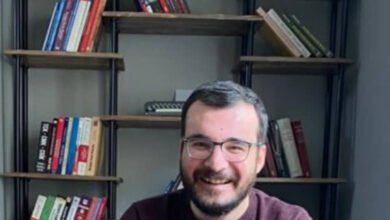 Engelli avukat Erhan Ürküt, arkasında kitapların olduğu bir yerde omuzundan yukarısı gözüküyor şekilde oturuyor.