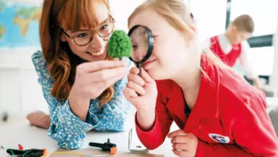 Fotoğrafta, küçük bir kız çocuğu büyütecin arkasından, küçük bir ağaç motifine bakıyor. Küçük kız çocuğu büyüteci elinde tutarken, yanındaki kişi gülümseyerek ağaç motifini büyütecin önünde tutuyor.