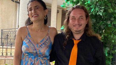 Fotoğrafta Ayşe Gümüş ve Turgay Gümüş yan yana kameraya bakarak poz veriyor. Çiftin yüzleri gülümsüyor. Ayşe Gümüş'ün mavi elbise var Turgay Gümüş'te ise siyah gömlek üzerinde turuncu kravat var.
