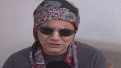 Görme engelli birey engelli Sermin Aslan, siyah gözlük, farklı eşarp takıyor ve gri bir tişört giymiş.