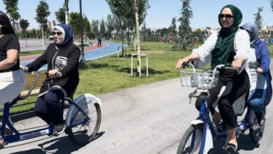 Fotoğrafta çift kişilikli bisiklet var. Bisiklette 2 gidon ve 2 pedal var. Görme engelli bireyler arka tarafta oturuyor ve ön tarafta rehber kişi destek oluyor.