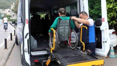 Bir minibüs arkasında özel yapım asansör ile tekerlekli sandalye kullanan engelli bireyi araç içine alıyorlar.