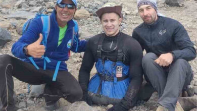 Fotoğrafta, belden aşağısı ampute olan engelli birey ve yanında ise dağa tırmanmasına destek olan refakatçi dağcı sporcular var.