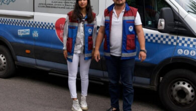 Trabzon Büyükşehir Belediyesi'nin engelsiz taksi aracının önünde iki personeli fotoğrafta yer alıyor.