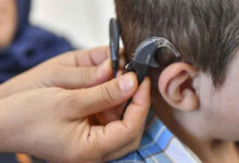 Fotoğrafta, işitme engelli bireyin kulağına işitme cihazı takılıyor.