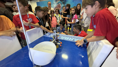 Tekerlekli sandalye kullanan engelli çocuk, arkadaşlarının geliştirdiği engelsiz oyunu test ediyor. Engelli çocuğun koluna takılan cihazla futbol benzeri bir oyunda, topa vurması sağlanıyor. Projeyi ilkokul çağındaki ilgi gösteren birçok çocuk incelemek için çevresine toplanmış.