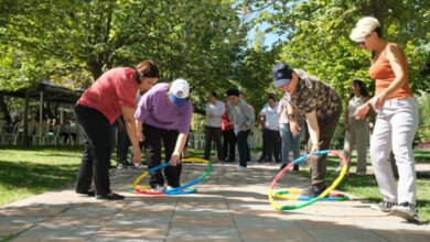 Yuvarlak ortası boş renkli halkalar ile engelli bireyler oyun oynuyor.