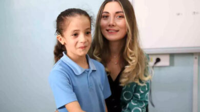 İşitme engelli Ecrin Oygur ve öğretmeni Güler Ayyıldız, sınıfta beyaz bir tahtanın önünde birlikte fotoğraf çekiliyorlar.