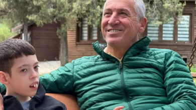 Harmancık Belediye Başkanı Haşim Ali Arıkan, ngelli bir çocuk ile yan yana oturuyor ve çocuğun elini tutuyor.