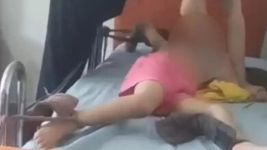 Küçük bir çocuk yatağa kollarından ve ayaklarından bez parçası ile bağlanmış ve başında yetişkin bir görevli var. Çocuğun yüzü kapatılmış.