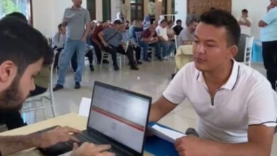 Bilgisayar başında oturmuş bir kişi, engelli birey için form dolduruyor. Arka planda ise farklı engelliliği olan bireyler sırayla işverenler ile görüşmek için bekliyor.