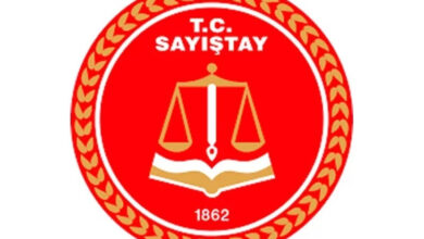 Görselde, Sayıştay’ın logosu var. Logo yuvarlak ve kırmızı zemin üzerinde bir tasarıma sahip. Logonun uç bölgelerinde altın sarısı kelebek figürlerinden bir daire var. Daha sonra kelebek figürünün sağ tarafında beyaz bir halka, beyaz halkanın içerisinde ise üst tarafta saat 12 yönünde “T.C SAYIŞTAY” yazıyor. Yazının altında dengede duran bir terazi ve altında ise sayfalar açık bir kitap var. Bunların altında ise “1862” yazıyor.