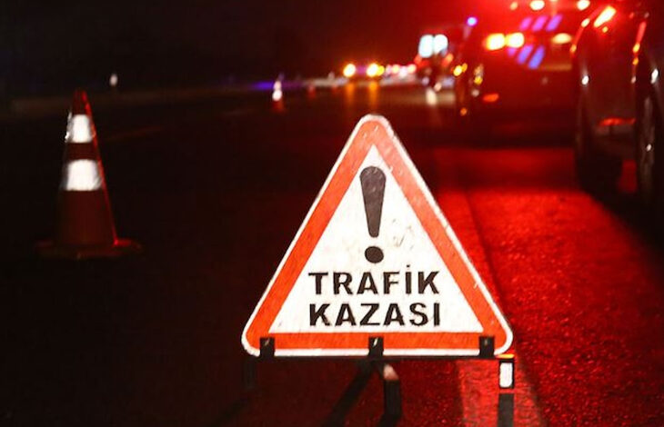 Yol ortasına katılmış "!TRAFİK KAZASI" yazısının olduğu bir tabela ve güvenlik dubaları duruyor.