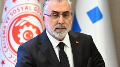 Çalışma ve Sosyal Güvenlik Bakanı Vedat Işıkhan, arkasında bakanlığa ait bayrak olan bir odada basın açıklaması yapıyor.