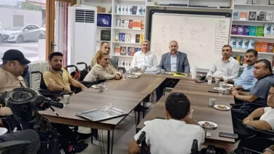 Şırnak'ın Cizre İlçe Müftüsü Süleyman Baran, tekerlekli sandalye kullanan engelli bireyler ile bir masanın etrafında konuşuyor.
