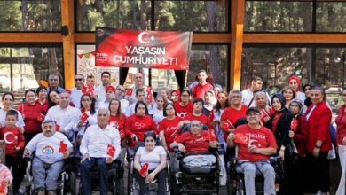 Engelli bireyler ve aileleri Türk bayrakları ve "Yaşasın Cumhuriyet" yazılı pankart ile birlikte fotoğraf çekiliyorlar.