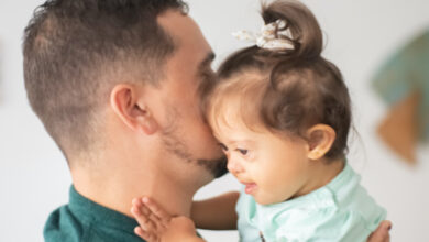 Fotoğrafta, down sendromlu bir çocuk babasının kucağında ve babasına sarılıyor.