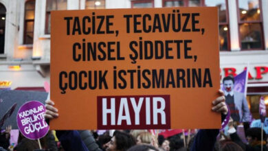 Kadınlardan oluşan kalabalık bir gösterici grubunun içerisindeki bir kişi “Tacize, tecavüze, cinsel şiddete, çocuk istismarına Hayır” yazılı bir pankart taşıyor.