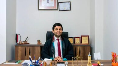 Görme engelli birey Avukat Mehmet Emre Kalaycı, avukatlık cübbesini giymiş ve ofisinde masa başında oturuyor.