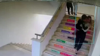 Fotoğrafta, merdiven basamaklarından aşağıya doğru inen bir kadının kucağında çocuk taşıdığı görülmektedir.