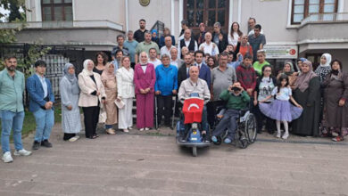 Fotoğrafta, birbirinden farklı yeti kaybına sahip engelli bireyler ve aileleri Sanat Galerisi önünde toplu bir fotoğraf çekimine katılıyorlar.