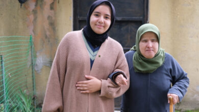 Görme engelli birey ve Kuran hocası ayakta birbirlerinin kollarına girerek fotoğraf için poz veriyorlar.