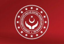Fotoğrafta, Aile ve Sosyal Hizmetler Bakanlığı’nın logosu var. Logo kırmızı zemin üzerinde ilk halka burgulu bir görüntüsü var. Halkanın iç kısmında ve halka boyunca küçük birçok beyaz renkli yıldız var. Daha sonra ise iki düz beyaz halkanın içinde “Türkiye Cumhuriyeti Aile ve Sosyal Hizmetler Bakanlığı” yazısı var. Tam ortada ise yan tarafa doğru açılmış iki el, üstünde ise uçları yukarı doğru bakan bir ay ve onun da üstünde bir yıldız var.
