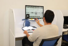 Görme engelli öğrenci bilgisayar başında özel bir program ile kitapları büyüterek ders çalışıyor.