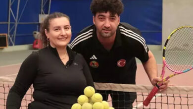 Esra Bozdemir Işık ve eşi Ömer Işık tenis filesinin yanında birbirlerine omuz omuza duracak şekilde poz veriyorlar.