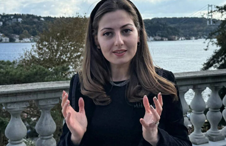 Fotoğrafta, işitme engelli birey Sibel Kaya var. Kaya her iki kolunu hafif yana doğru açmış ve el parmakları açık şekilde duruyor.
