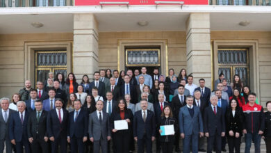 Eskişehir Valiliği tarafından düzenlenen “Ellerin Sesim Olsun” projesi kapsamında işaret dili kursunu tamamlayan memurlara belge teslim töreni Valilik önünde düzenleniyor. İşaret dili sertifikasını alan kişiler toplu fotoğraf çekimi için arkadan öne doğru ve yan yana olacak şekilde ayakta duruyorlar.