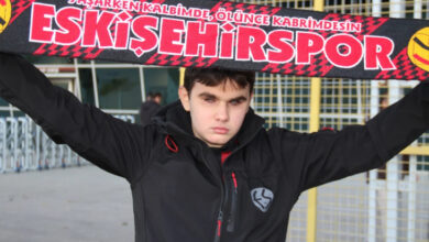 Görme engelli birey Kaan Kuş, elinde Eskişehirspor atkısını tutarak yukarı doğru kaldırmış ve açık şekilde atkıyı tutuyor.