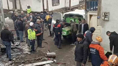Fotoğrafta, cenaze nakil arabasına tabut içinde ölen kişinin naaşı yükleniyor. Arabanın çevresinde polis, AFAD ekipleri ve itfaiye ekipleri var.