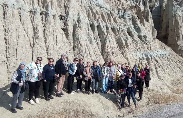 İşitme engelli bireyler ve aileleri Peri Bacaları gezisinde birlikte fotoğraf çekiliyorlar.