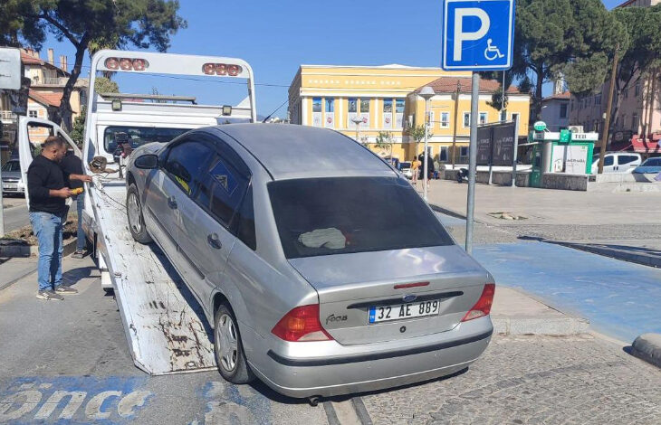 Gri renkli Ford Focus marka bir otomobil engelli park yerine aracı bıraktığı için trafik polisleri tarafından çekici aracılığıyla kaldırılıyor.