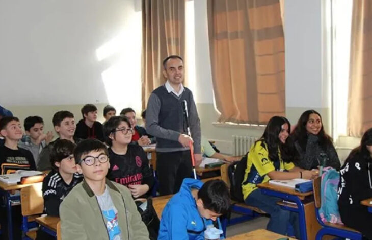 Görme engelli öğretmen Ahmet Tayfur Arslan bir sınıfta sıraların arasında dolaşarak öğrencilerine ders anlatıyor.