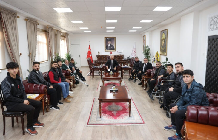 Muş Bedensel Engelliler Spor Kulübü’nün, Muş Valisi Avni Çakır’ı makamında ziyaret ederken çekilmiş bir fotoğraf. Fotoğrafın en uç uzak noktasında Vali oturuyor ve sporcularda karşılıklı olarak oturuyor.