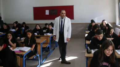 Görme engelli öğretmen Yunus Yılmaz, sınıfta ders anlatırken sıraların arasında dolaşıyor. Sınıftaki öğrenciler ise önlerindeki kitaba bakarak öğretmenin anlattıklarını takip ediyorlar.