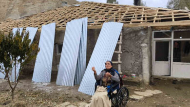 Tekerlekli sandalye kullanıcısı engelli birey Nişo Teymur, evinin çatısı yapılırken dışarıda oturuyor.