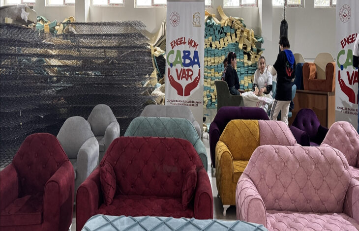 Fotoğrafta, farklı renklerdeki koltuklar var. Koltukların arka tarafında ise bir masa ve masanın yanında bir bayrak var.