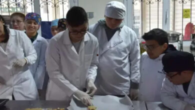 Fotoğrafta, engelli bireyler mutfakta yemek yapıyor. Üzerlerinde ise mutfakta giyilen beyaz önlükler var.