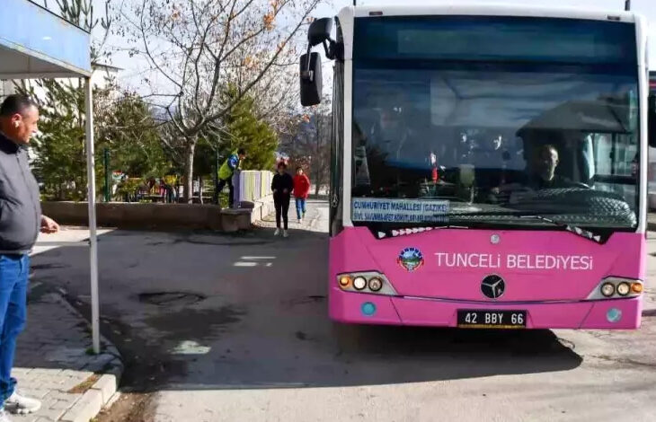 Mor renkli büyük bir toplu taşıma amacıyla kullanılan otobüs durağa doğru yaklaşıyor. Durakta ise insanlar otobüsü bekliyor.