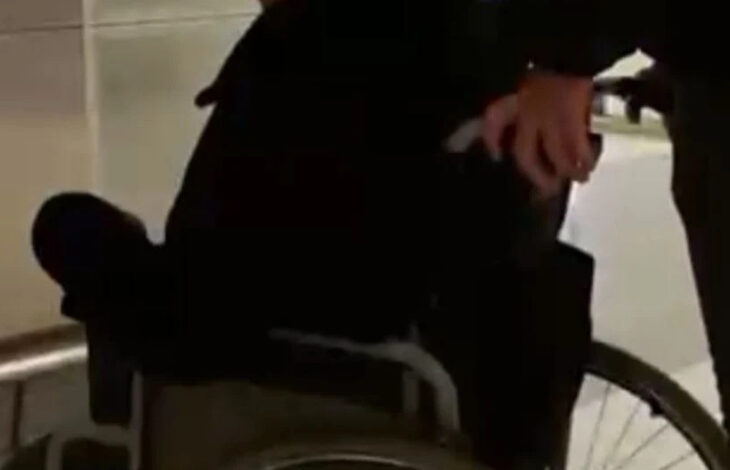 Tekerlekli sandalye üzerinde oturan engelli birey ve tekerlekli sandalyeyi arkasındaki bölümden iterek hareket ettiren yakını var. Engelli birey ve yakınının yüzü gözükmüyor.