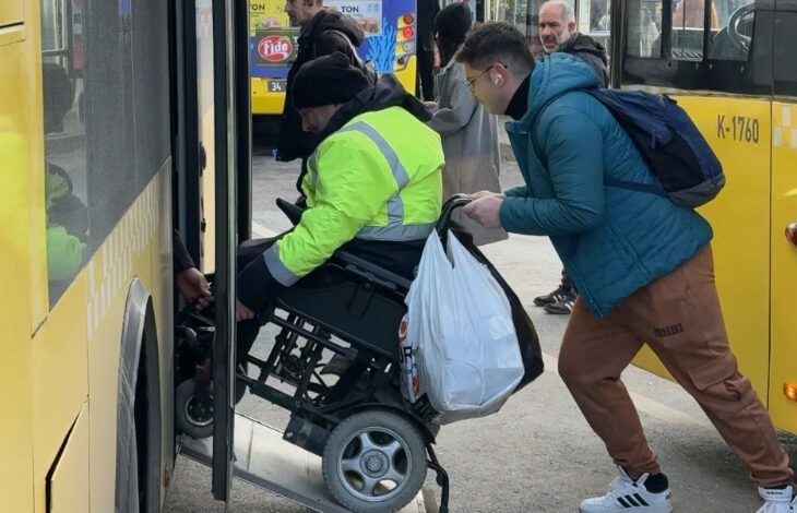 Akülü tekerlekli sandalye kullanan engelli birey, Büyükşehir Belediyesi'ne ait otobüse rampayı kullanarak binmeye çalışıyor. Ancak rampa çok dik olduğu için akülü tekerlekli sandalyenin arkasından bir kişi itekliyor.