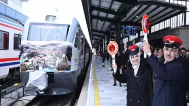 Fotoğrafta, Aile ve Sosyal Hizmetler Bakanı Mahinur Özdemir Göktaş ile Ulaştırma ve Altyapı Bakanı Abdulkadir Uraloğlu trenin önünde ellerinde uyarı levhalarıyla gülümseyerek kameraya doğru bakıyorlar.