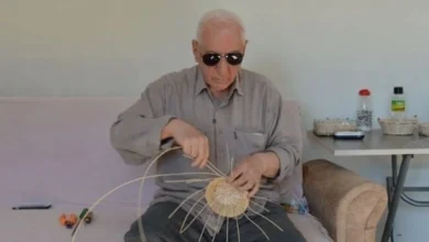 Fotoğrafta, yaşlı bir adam (79 yaşındaki Mahmut Tezcan) el yapımı bir sepetle uğraşıyor. Adam, gri bir gömlek giymiş ve güneş gözlüğü takmış. Elindeki bambu çubuklarıyla sepetin iskeletini örerken dikkatli bir şekilde çalışıyor. Arkada sade bir oturma odası ortamı görülüyor; bir masa üzerinde çeşitli eşyalar ve sepet yapımı malzemeleri yer alıyor.